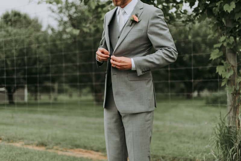 Man buttoning up his gray custom suit