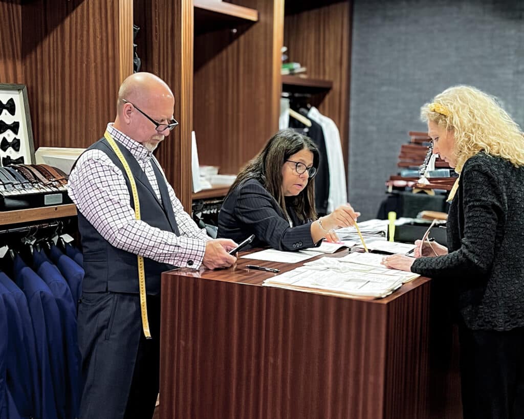 Three Alan David employees discussing a set of client measurements
