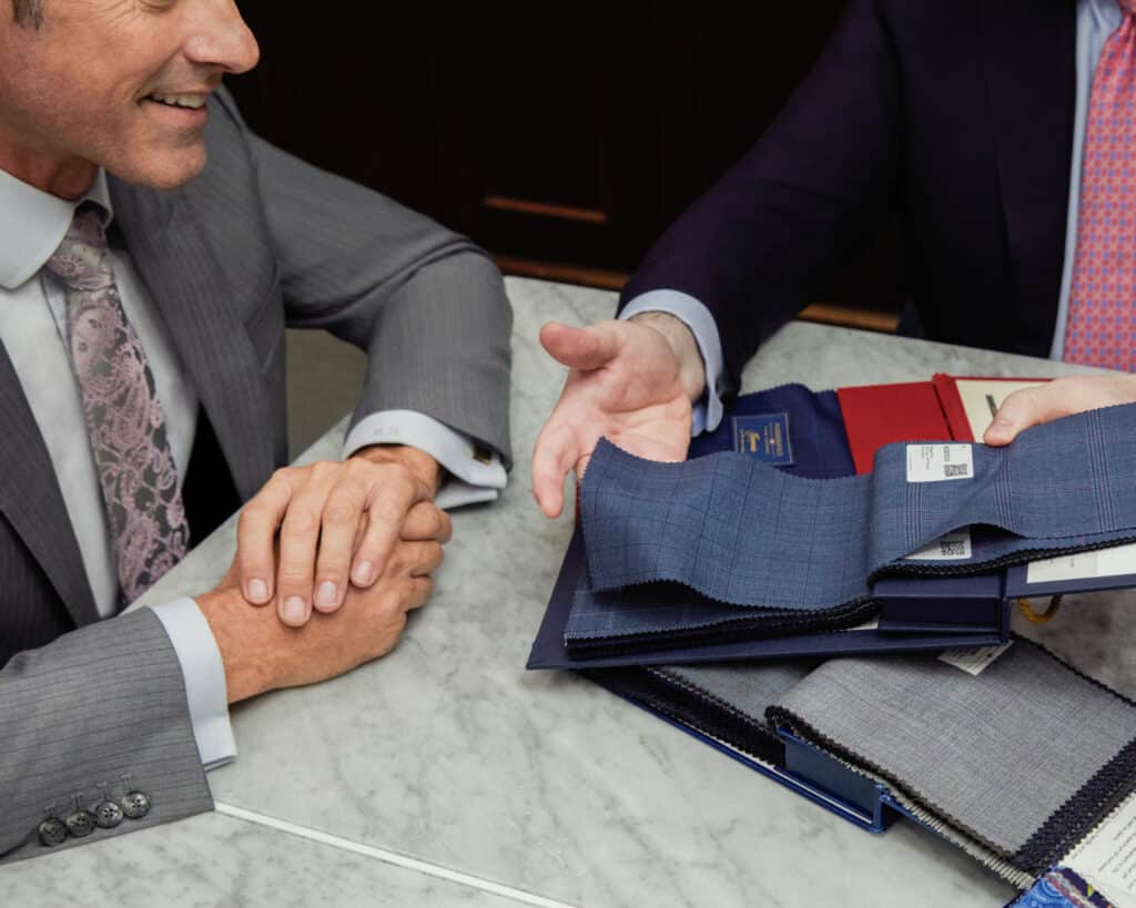 Salesman showing a client fabric swatches from a Holland & Sherry book