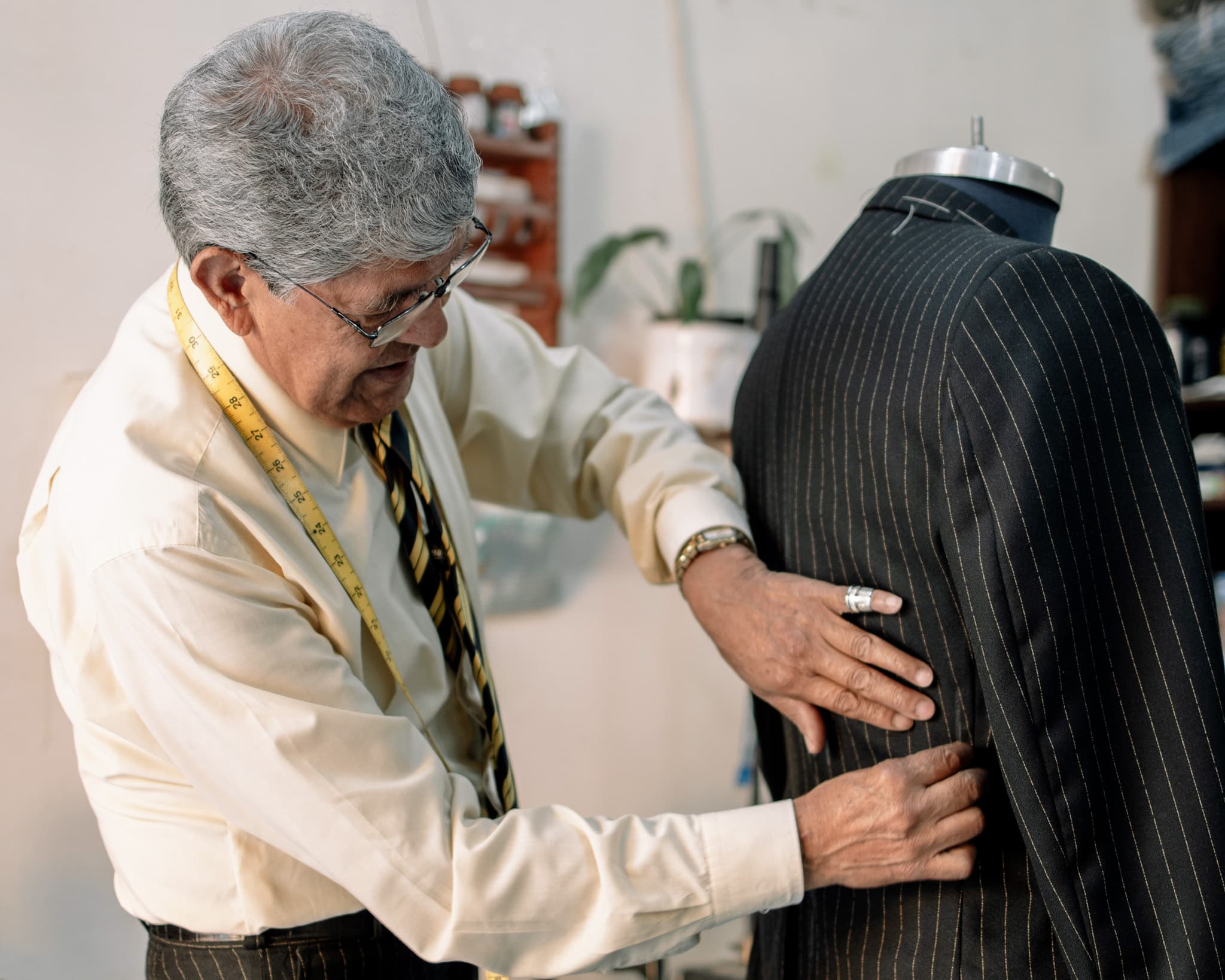 Custom tailor pinning the side of a suit jacket, preparing it for alterations.