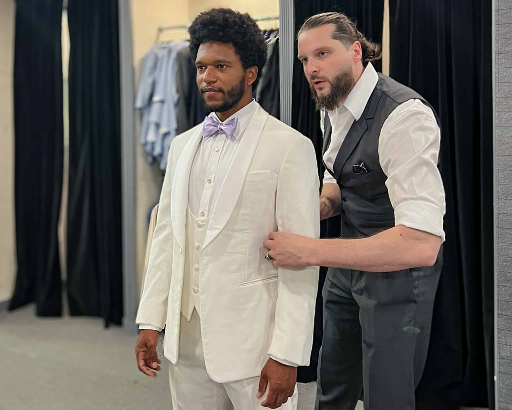 Fitter doing a final fitting making sure garment fits correctly. White 3 piece tuxedo-shawl lapel-linen.