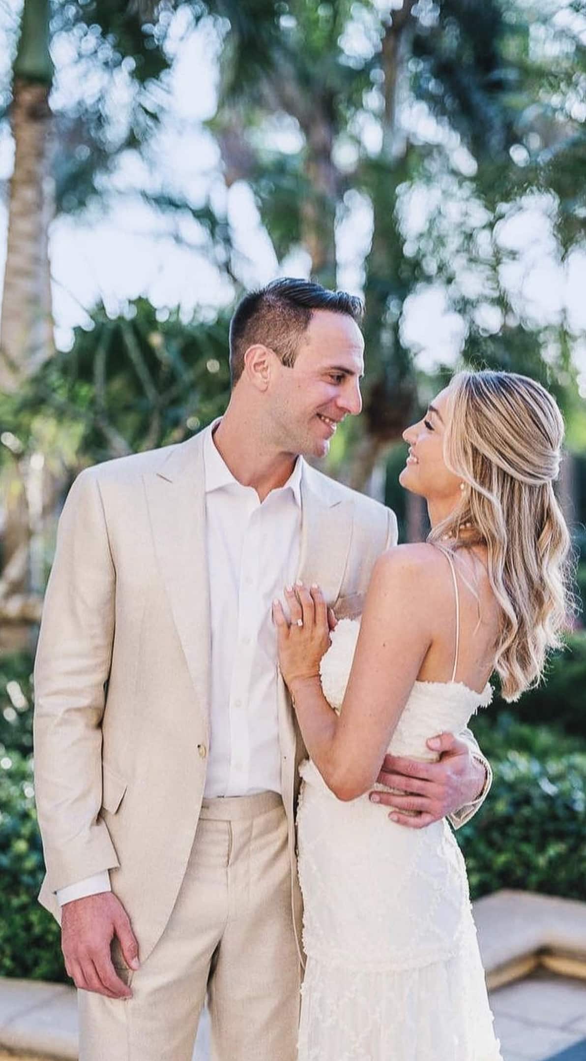 Groom and bride on beach looking at each other. Groom in off white custom made linen suit, bride in wedding dress.