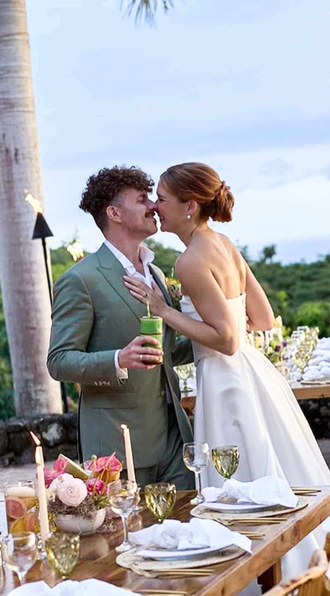 Bride and groom getting ready to kiss. Groom in light green bespoke wedding suit. Bride in wedding gown.