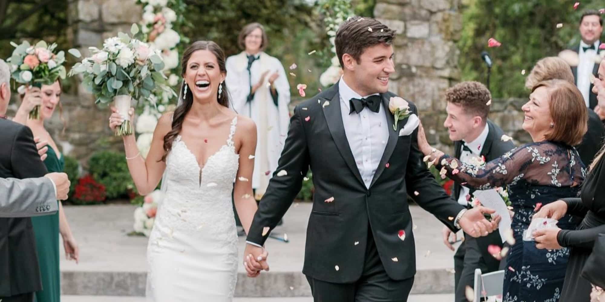 Bride and groom celebrating with wedding guests. Groom wearing Loro Piana black bespoke tuxedo, bride in low cut wedding dress.