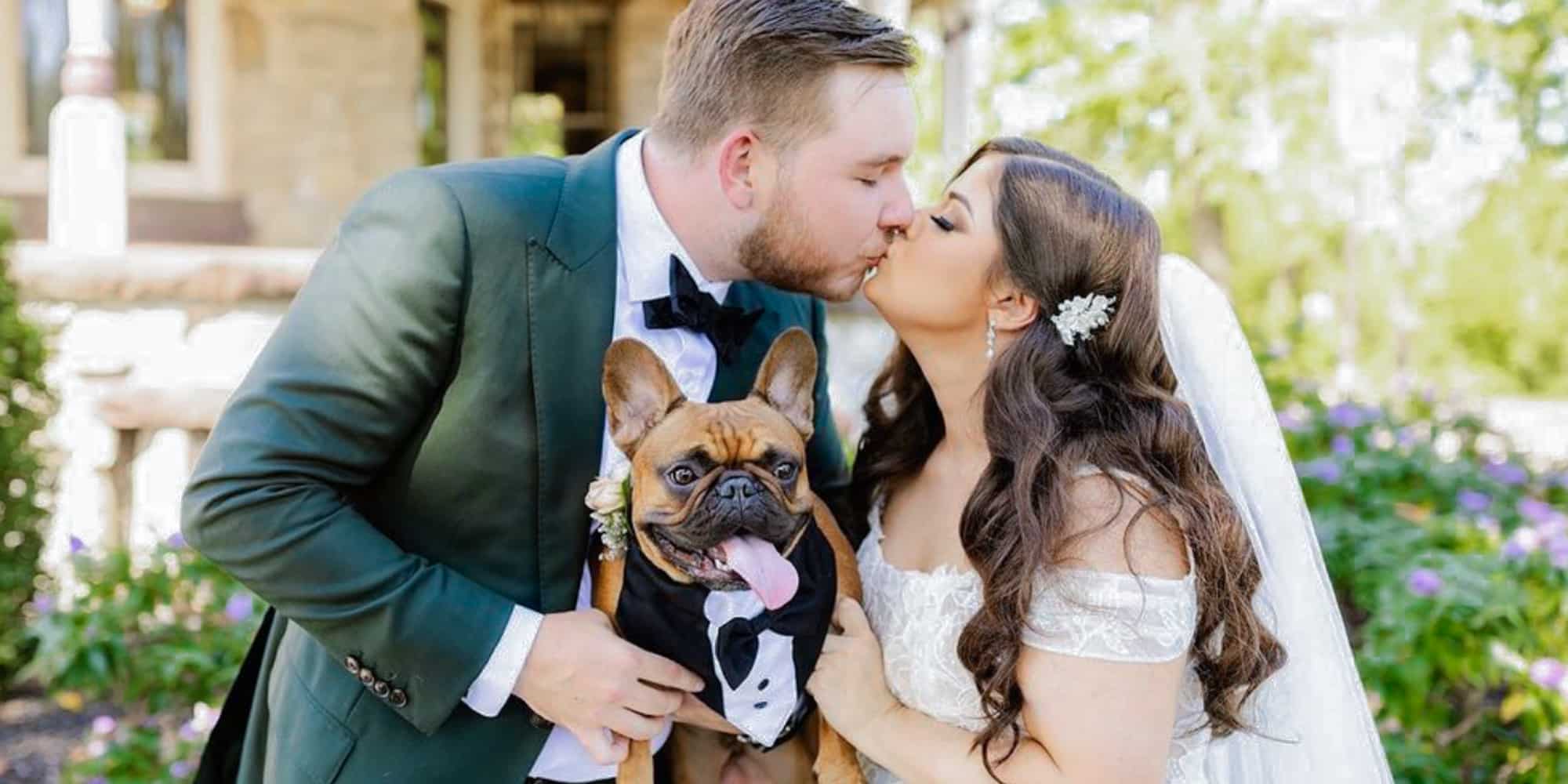 Bride and groom kissing. Groom wearing dark green bespoke suit with white shirt and black bowtie. Fabric by Scabal. Bride in low cut wedding dress.