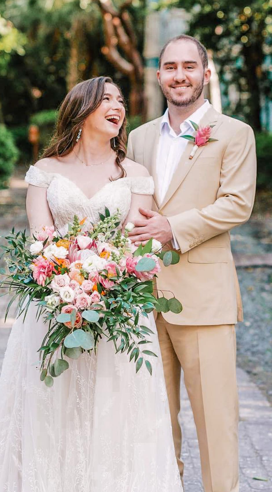 Bride and groom outdoors. Groom wearing Loro Piana linen off-white custom suit with open collared off white shirt. Bride in long wedding gown.