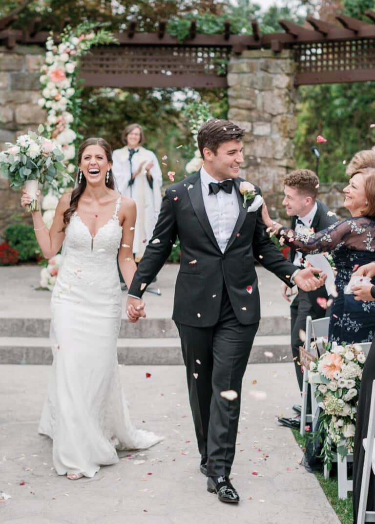 Bride and groom celebrating with wedding guests. Groom wearing Loro Piana black bespoke tuxedo, bride in low cut wedding dress.