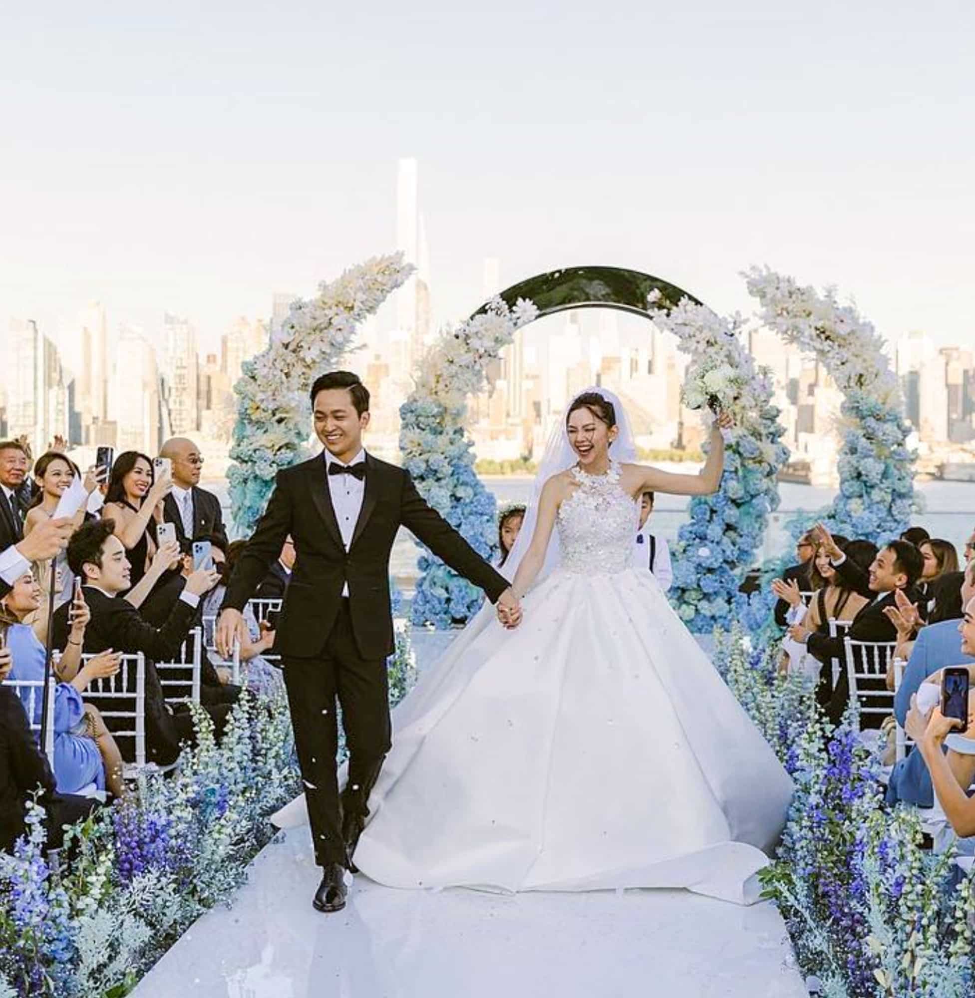 Bride and groom walking down aisle. Groom wearing classic bespoke tuxedo, bride in wedding dress.