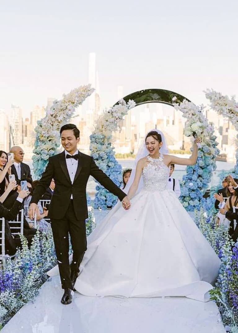Bride and groom walking down aisle. Groom wearing classic bespoke tuxedo, bride in wedding dress.