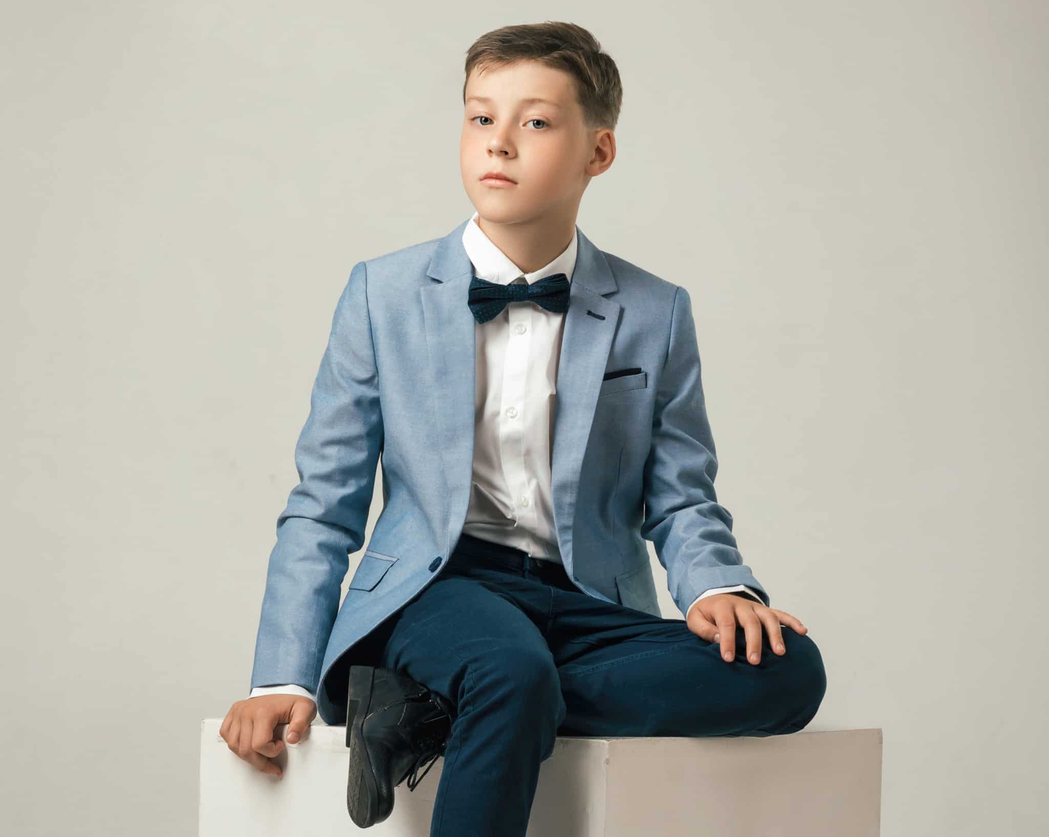 Boy wearing light blue custom made sportscoat with navy trousers and a white dress shirt.
