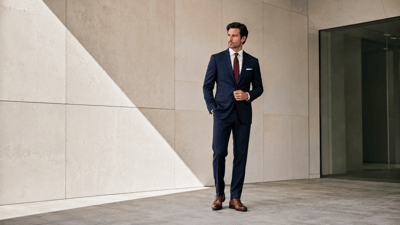 men wearing navy suit with brown shoes, white shirt and red tie.png