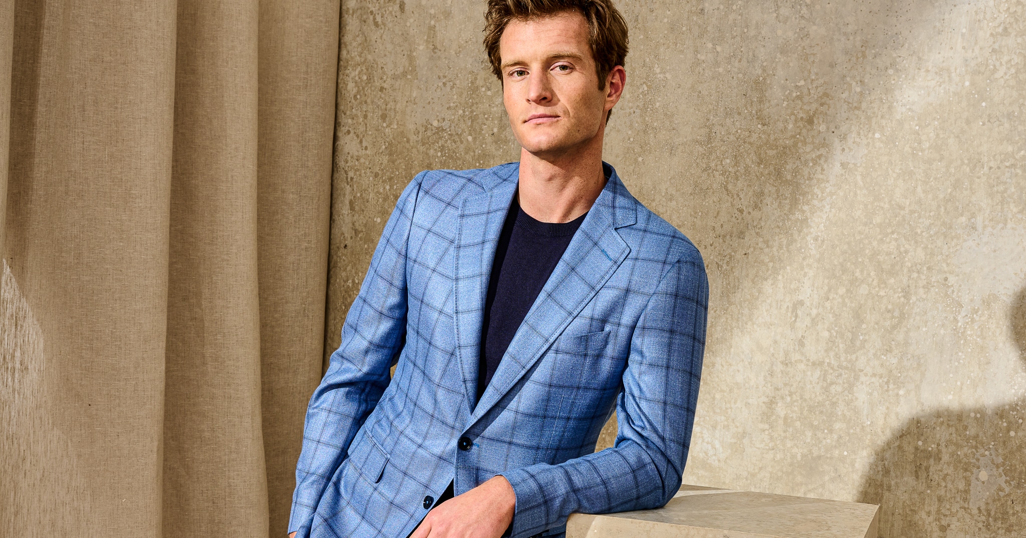 Scabal model wearing blue custom made sportscoat with navy windowpane and navy t-shirt.