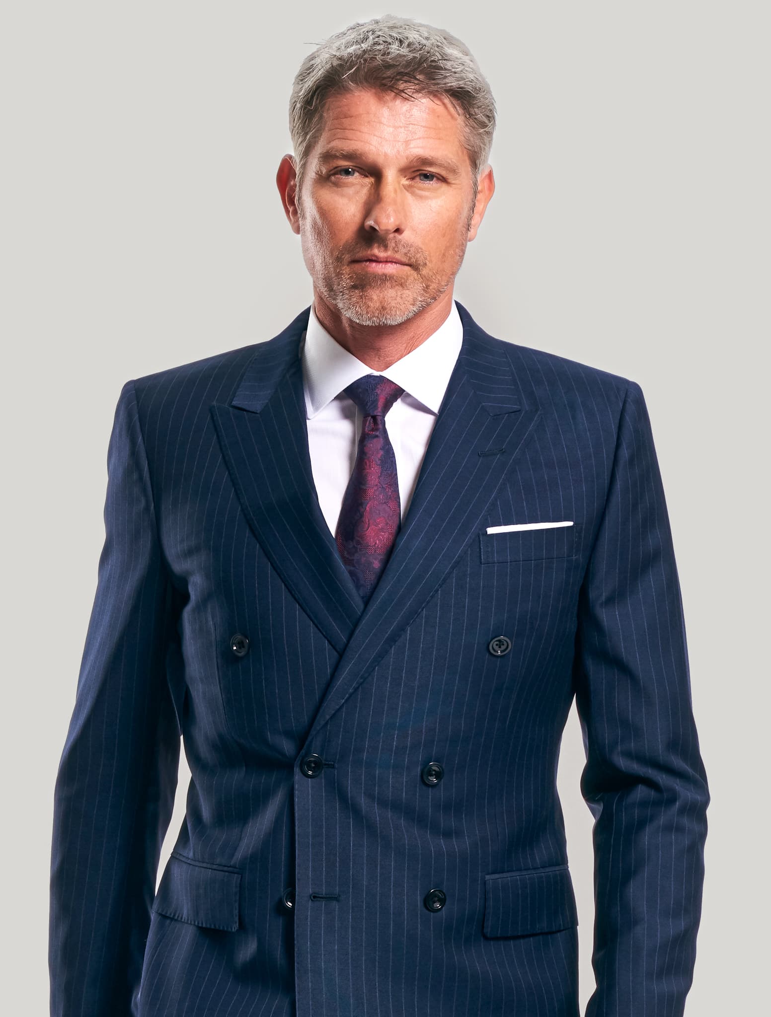 Client wearing blue double breasted pinstripe custom suit with white shirt and red paisley tie.