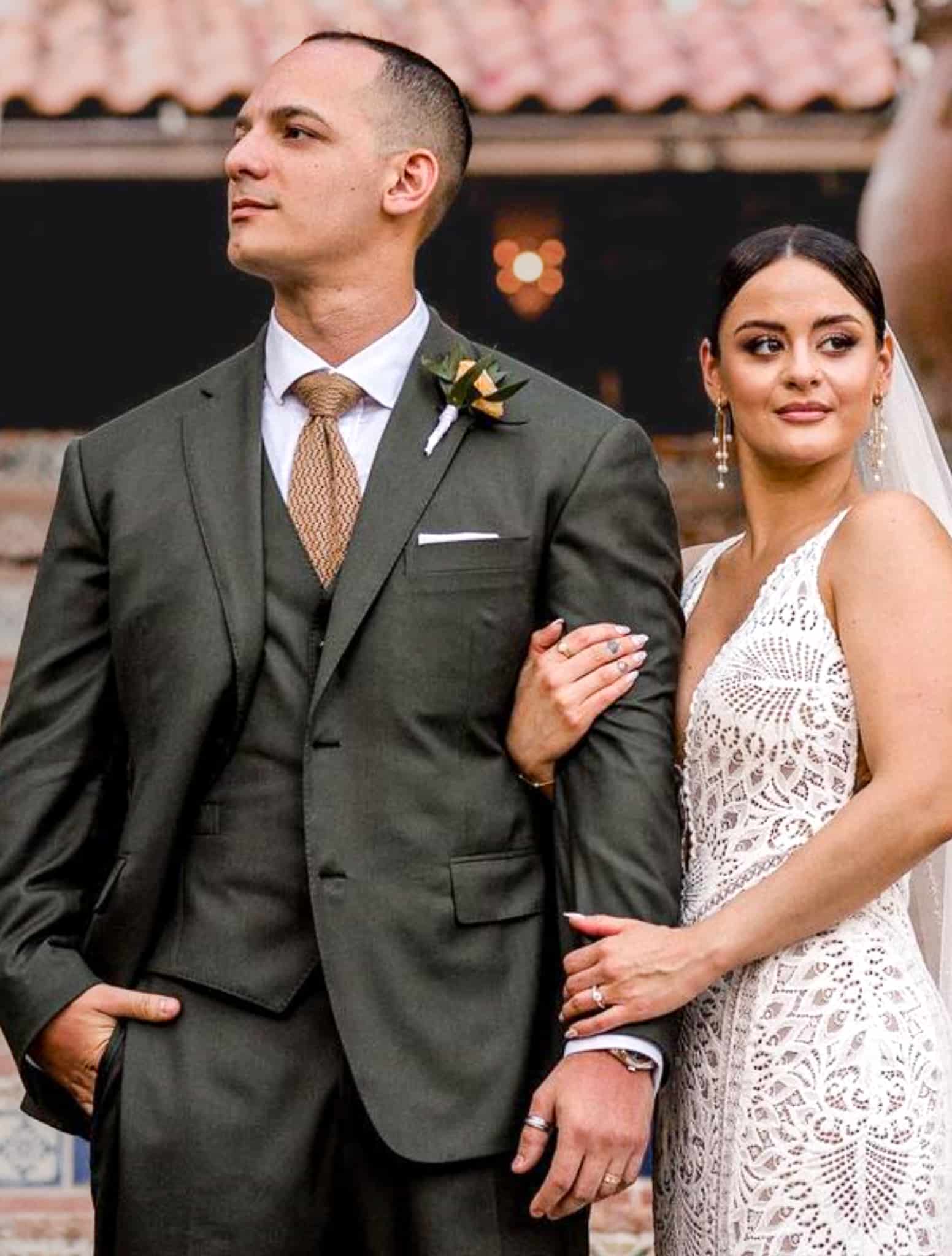 Bride and groom arm in arm. Groom wearing green three piece suit with white shirt and light green tie.