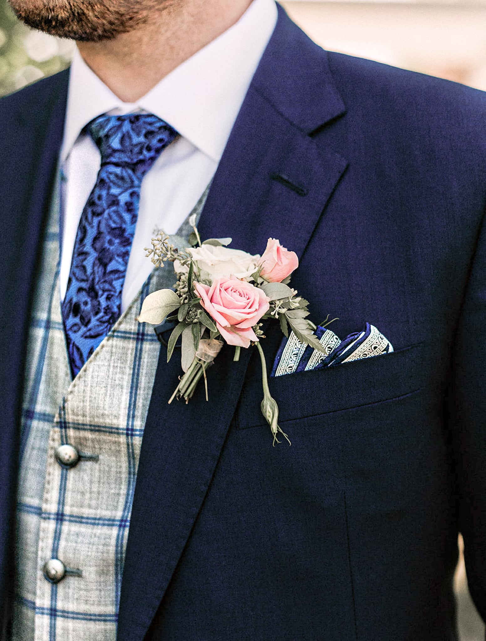 Close up of client wearing custom wedding suit in navy blue with a light grey custom vest and navy windowpane. White shirt and blue paisley tie.