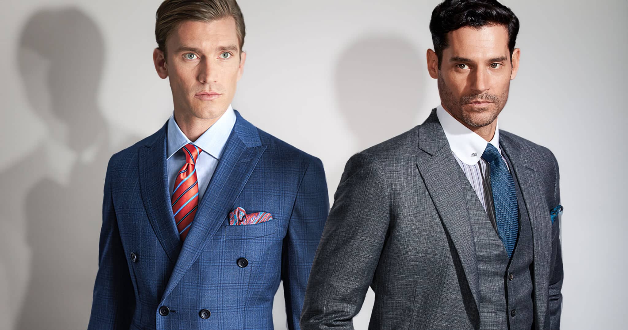 Two clients in wedding suits. One wearing a double breasted blue paid suit with orange tie. One wearing a grey 3 piece suit with a grey striped shirt and blue tie.
