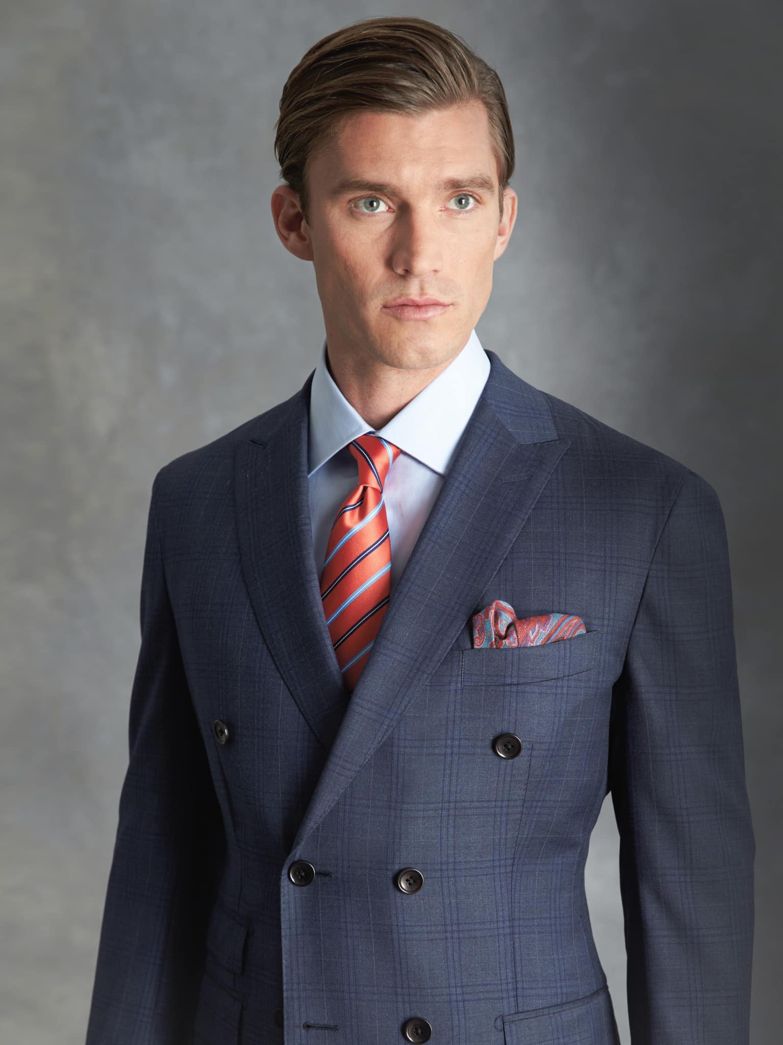 Client in blue plaid bespoke suit double breasted with light blue shirt and orange striped tie.