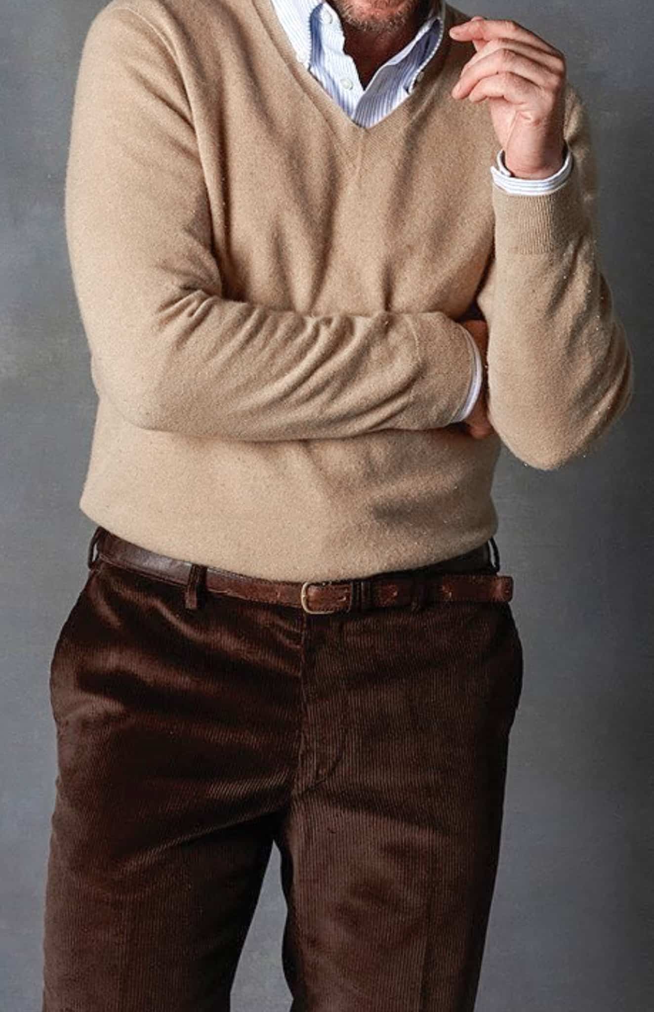 Client wearing dark brown custom made trousers with white shirt and light brown V neck sweater.