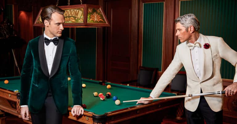 Two groomsmen shooting pool. One wearing a dark green custom tailored dinner jacket in Loro Piana fabric with a white shirt and black bowtie. One wearing a white Zegna bespoke dinner jacket with a very wide 3 inch shawl lapel and black trousers. White shirt with a white bowtie.