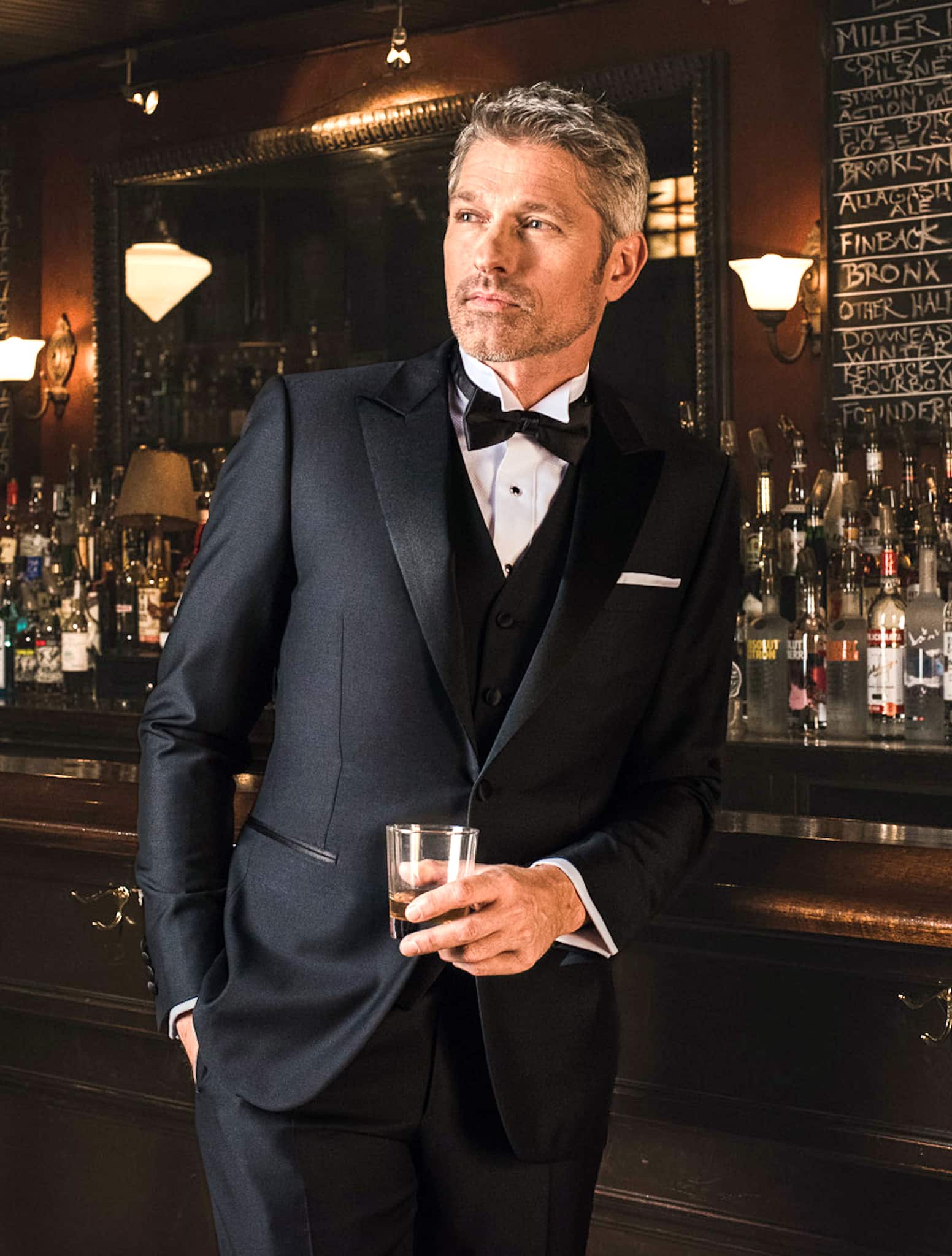 Groom wearing Drago classic black single breasted bespoke tuxedo with white shirt and black bowtie.
