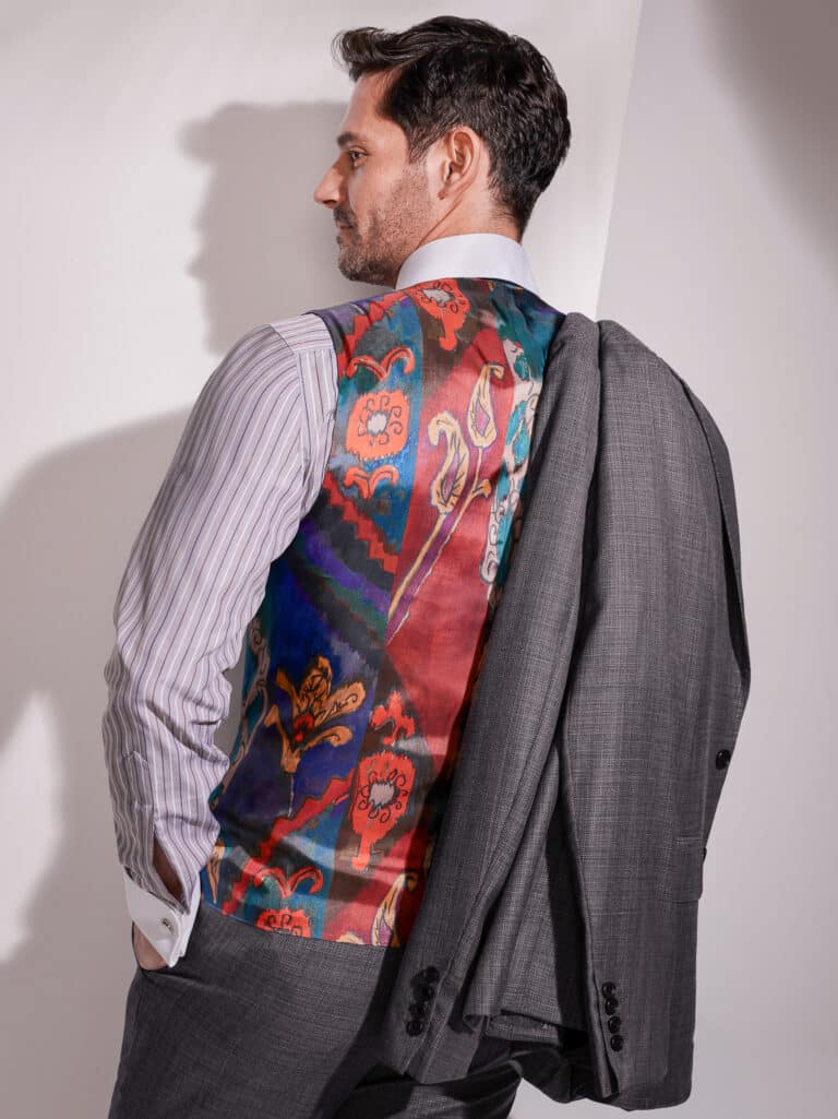 Model showing off back of custom vest lining paisley red and blue design.
