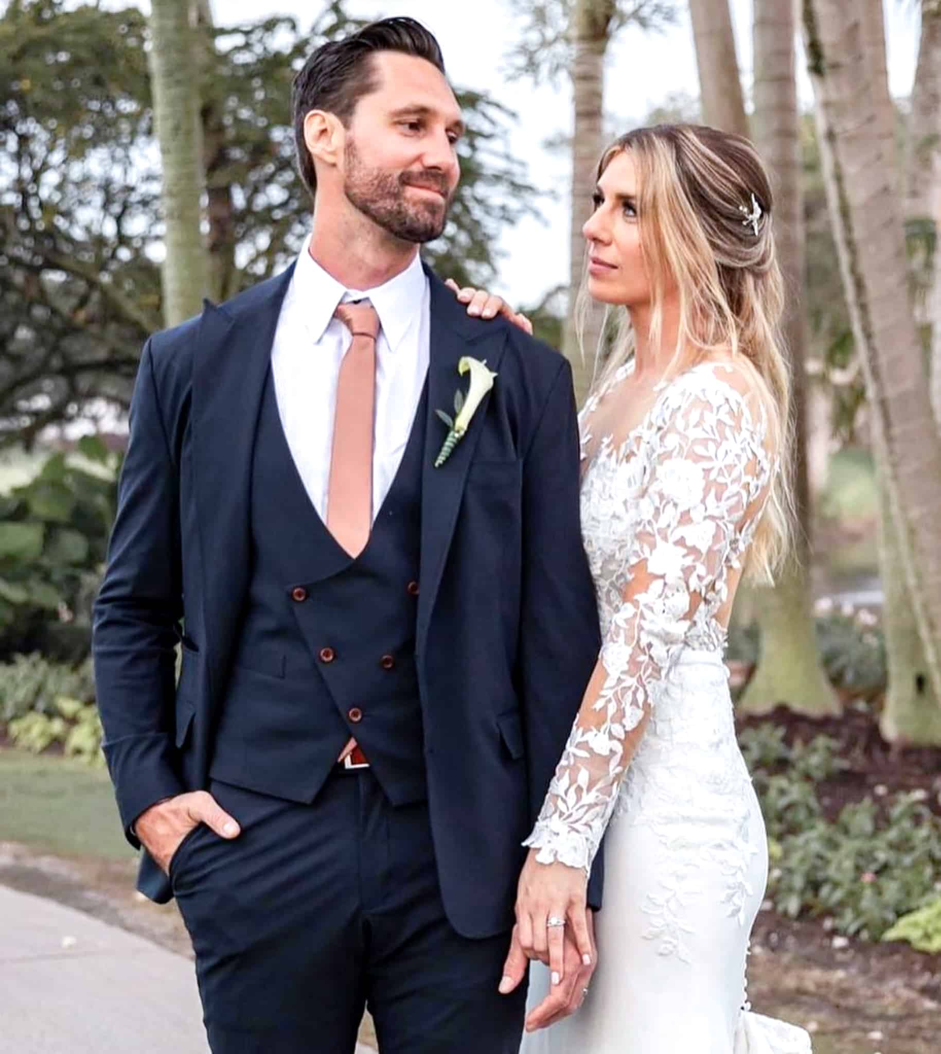 Bride and groom with trees in background. Groom in navy wedding suit with double breasted vest and tan tie. Bride in wedding dress.