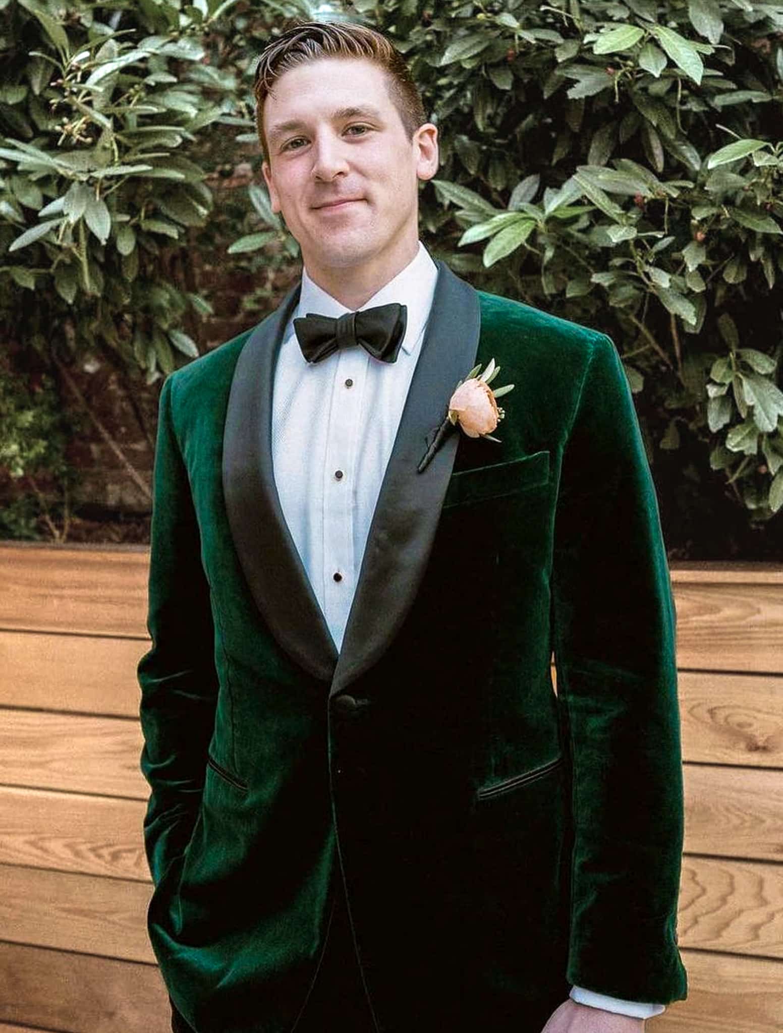 Groom wearing his custom made hunter green velvet tuxedo jacket with white shirt and black bowtie.