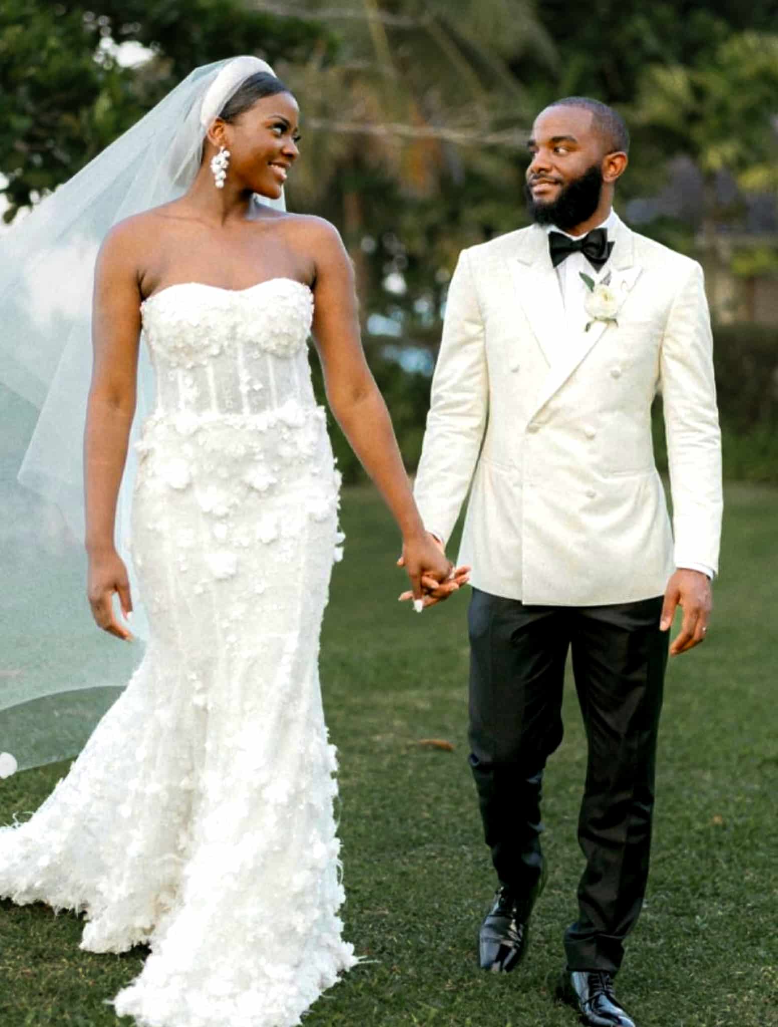Bride and groom on lawn. Groom in Vitale Barberis white double breasted bespoke dinner jacket with black trousers, white shirt and black bowtie. Bride in sleeveless wedding dress.