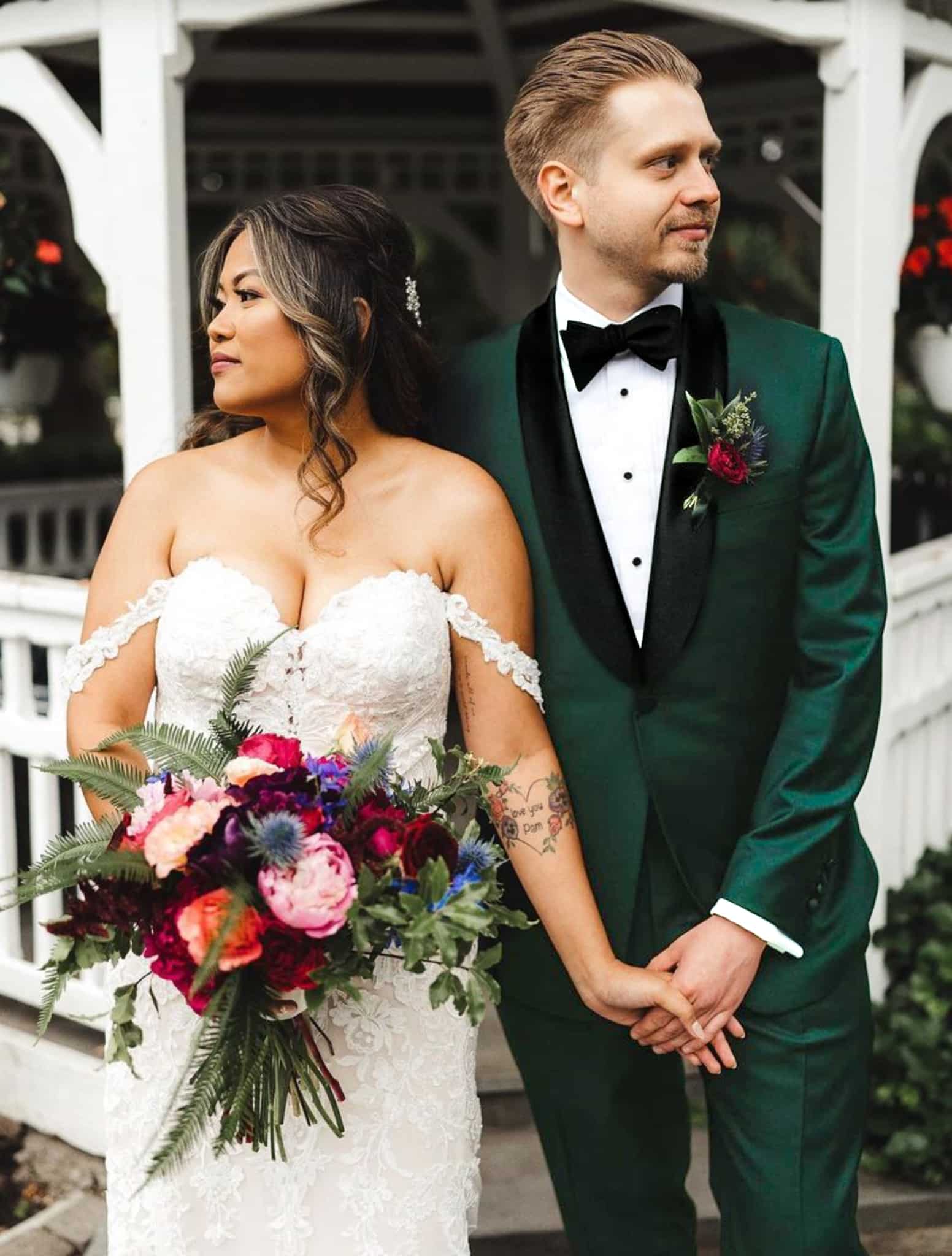 Bride and groom holding hands. Groom in Zegna black shawl lapel custom wedding tuxedo with white shirt and black bowtie. Bride in low cut wedding dress.