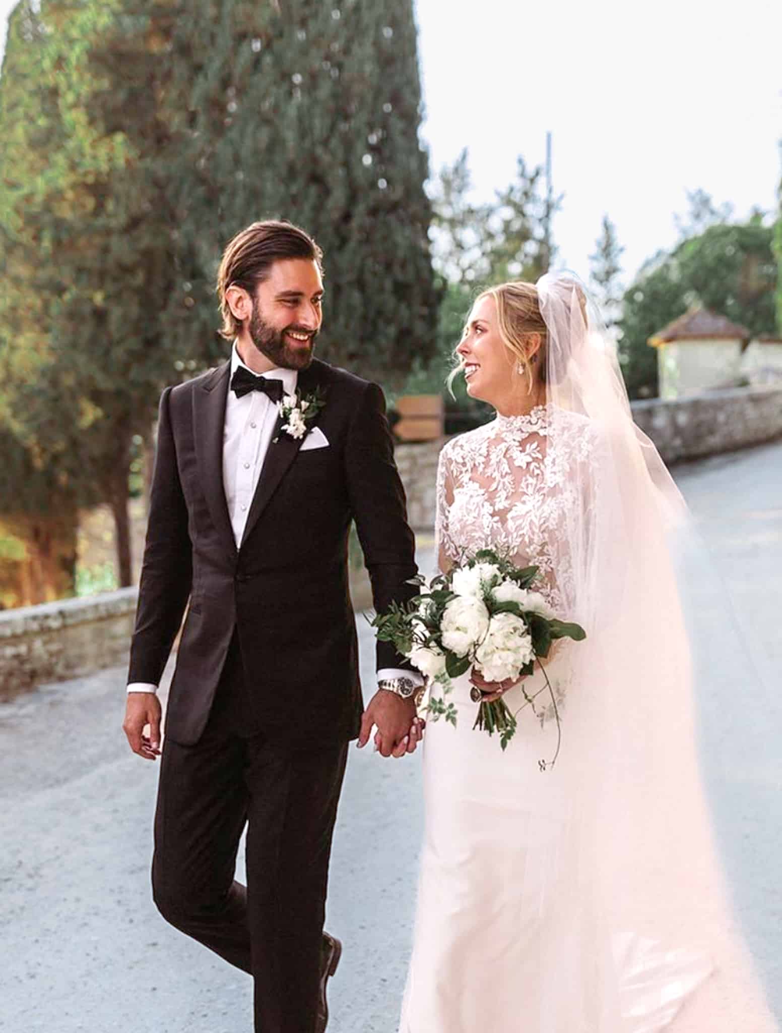 Bride and groom walking along path, groom in classic black tuxedo and bride in classic wedding dress.