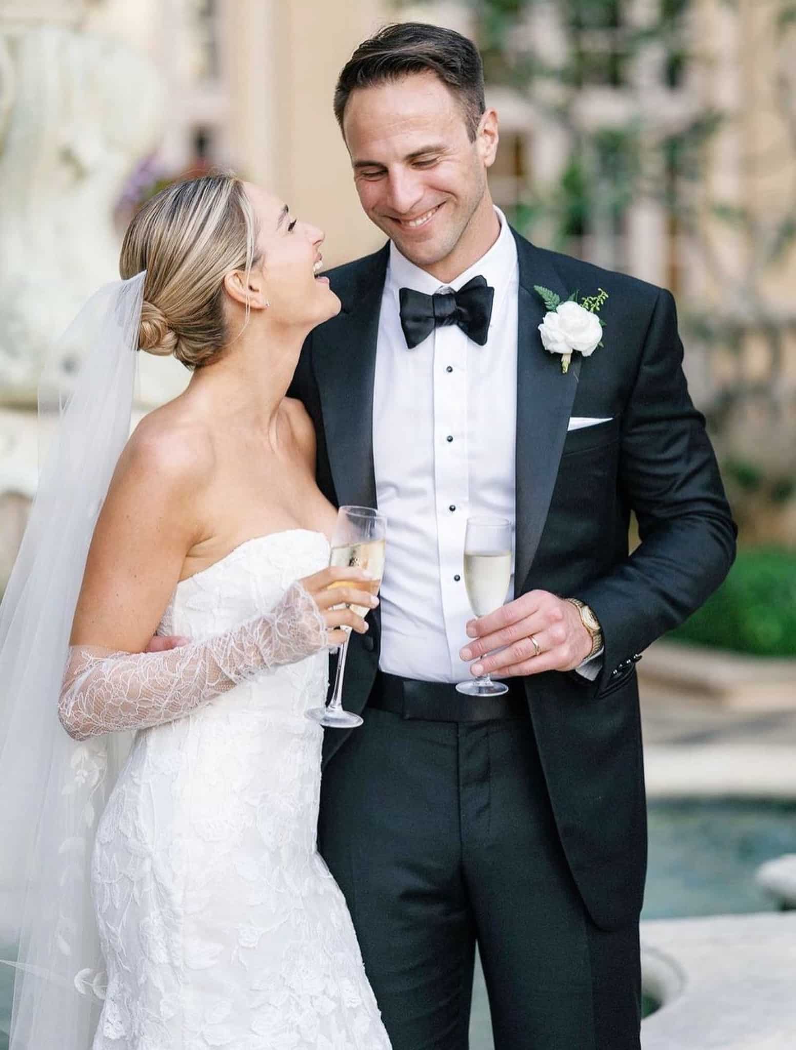 Bride and groom toasting. Groom in midnight navy Loro Piana tuxedo with white shirt and black bowtie. Bride in low cut wedding dress.
