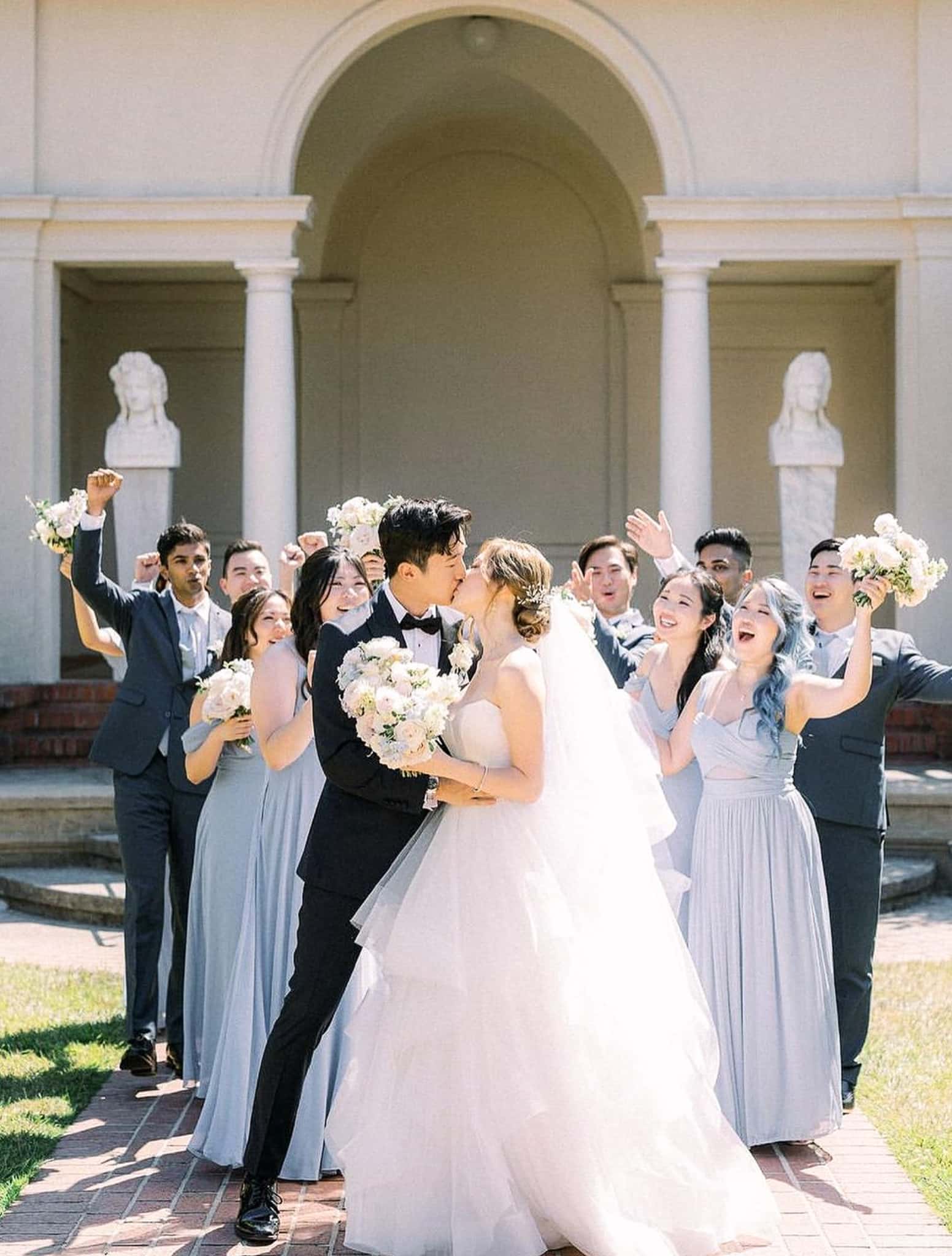 Bride and groom kissing outside church in classic wedding attire custom garments.
