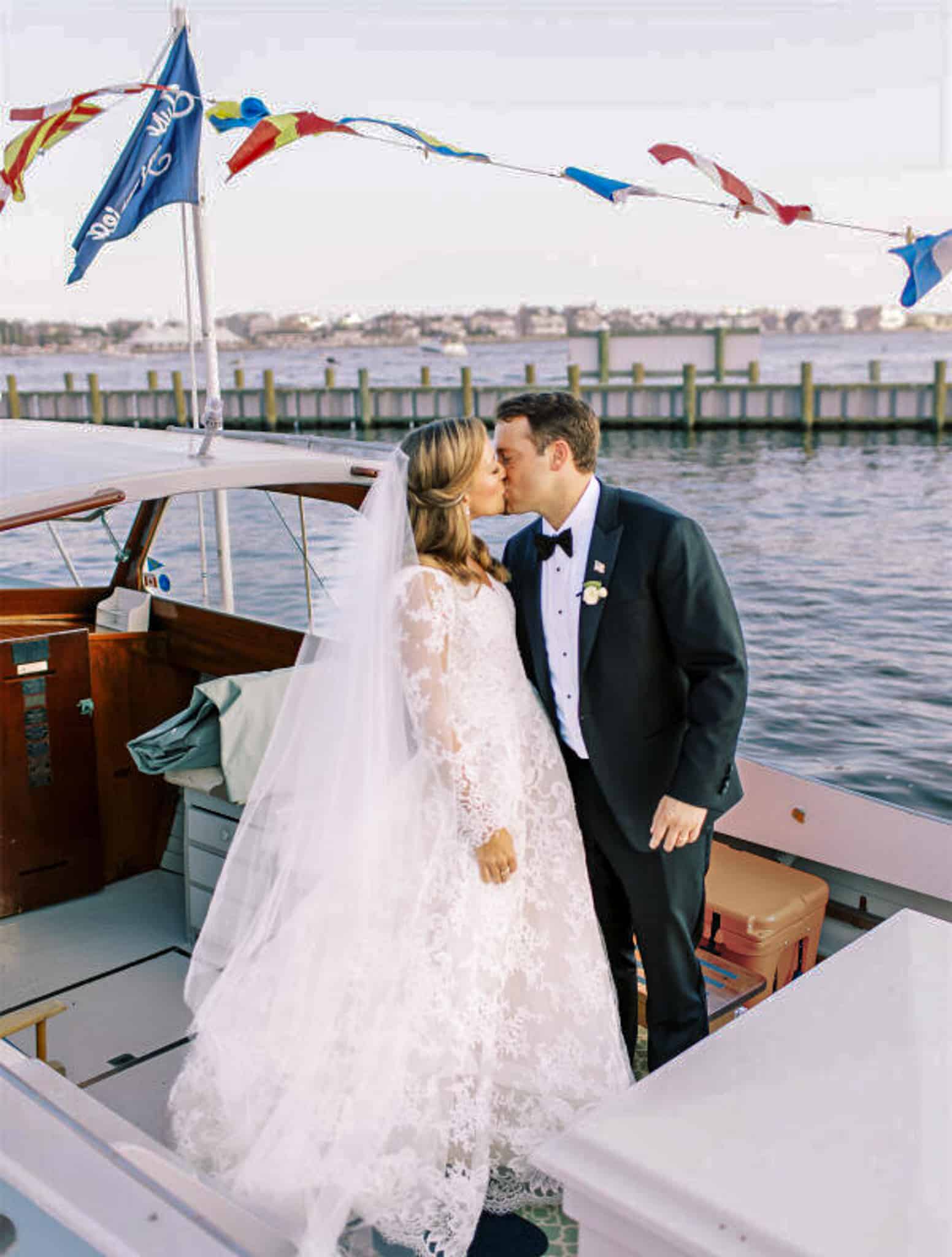 Bride and groom kissing on boat in France. Groom wearing Zegna black wedding tuxedo.