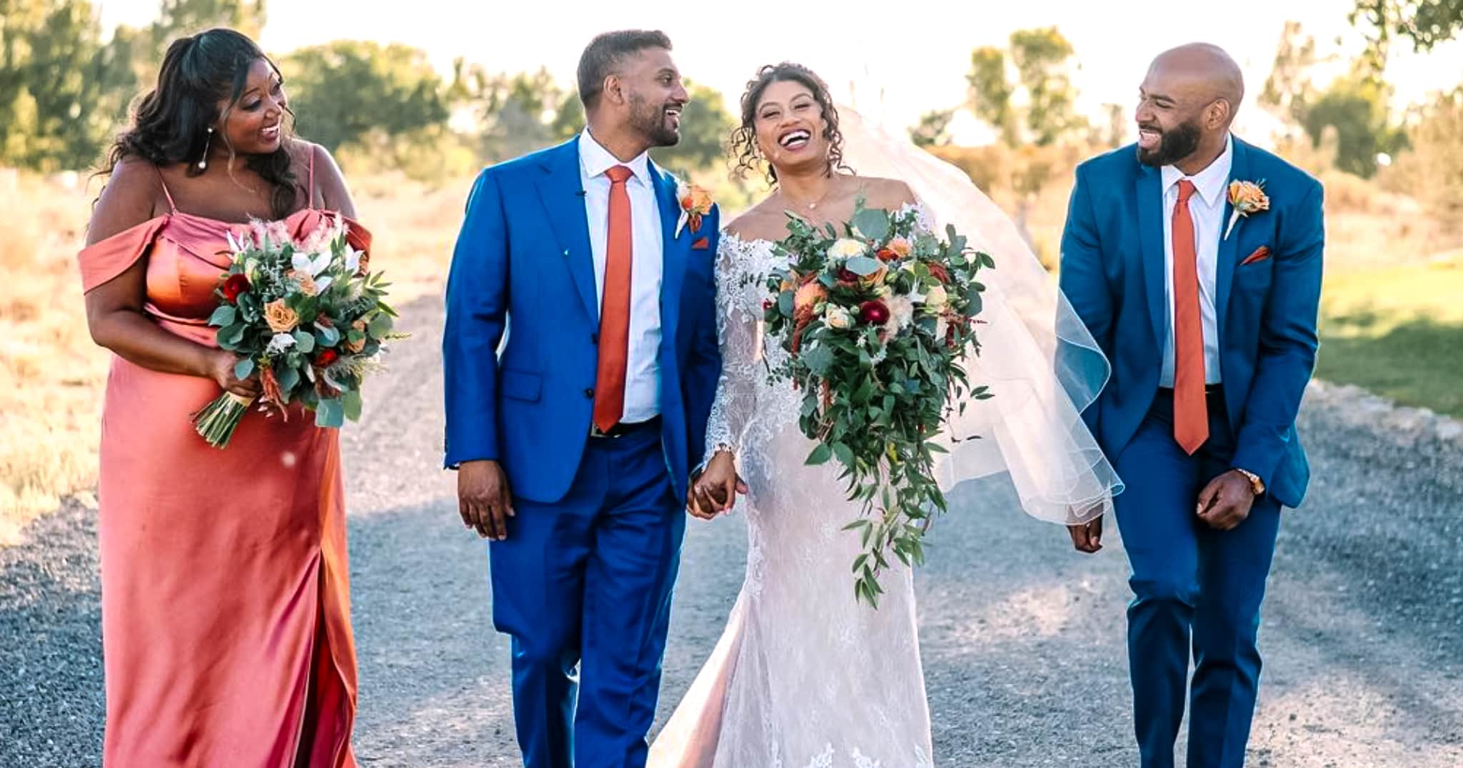 Bride and groom outdoors with mother and father. Groom wearing bespoke wedding suit in bright blue color with white shirt and solid orange skinny long tie. Bride in classic off the shoulder wedding gown.