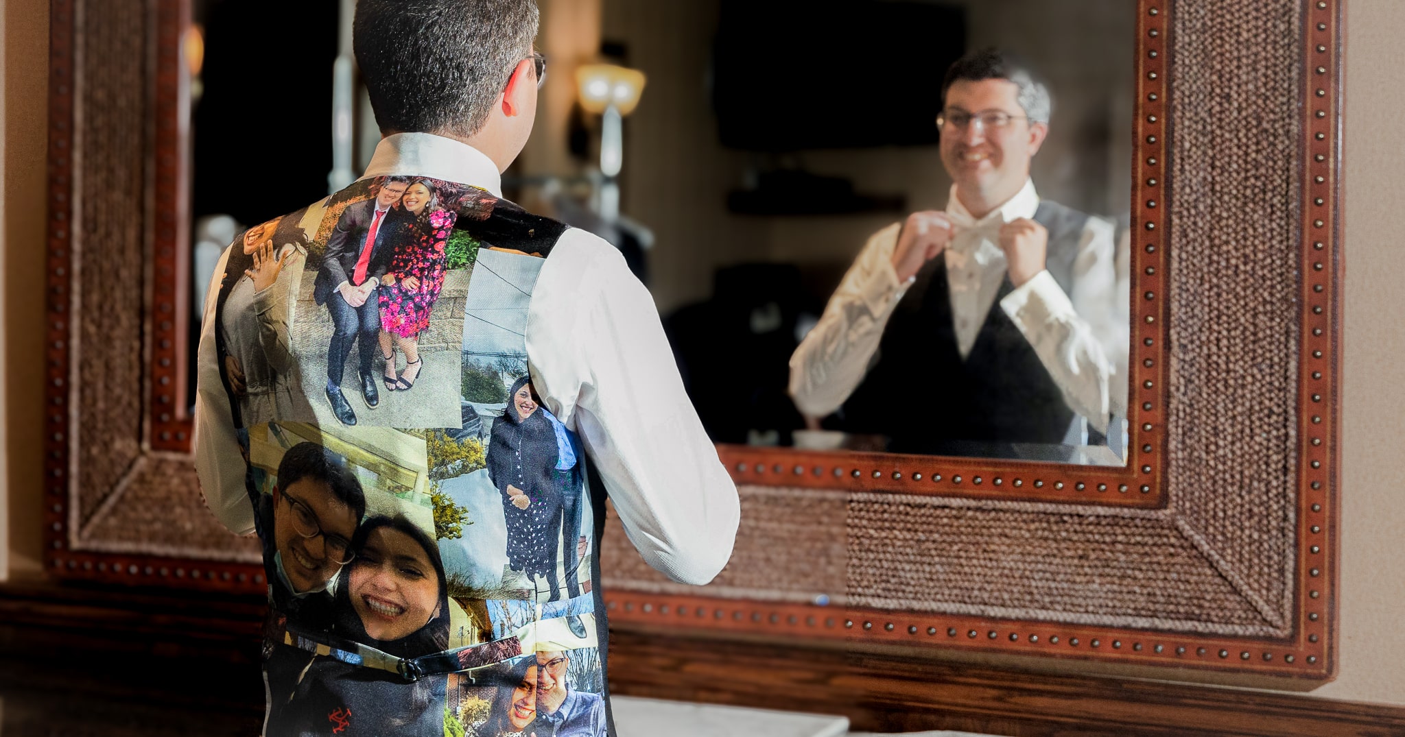 Owners son Benjamin Horowitz adjusting his bowtie in mirror. Wearing vest with photos of bride and groom screened onto back of vest.