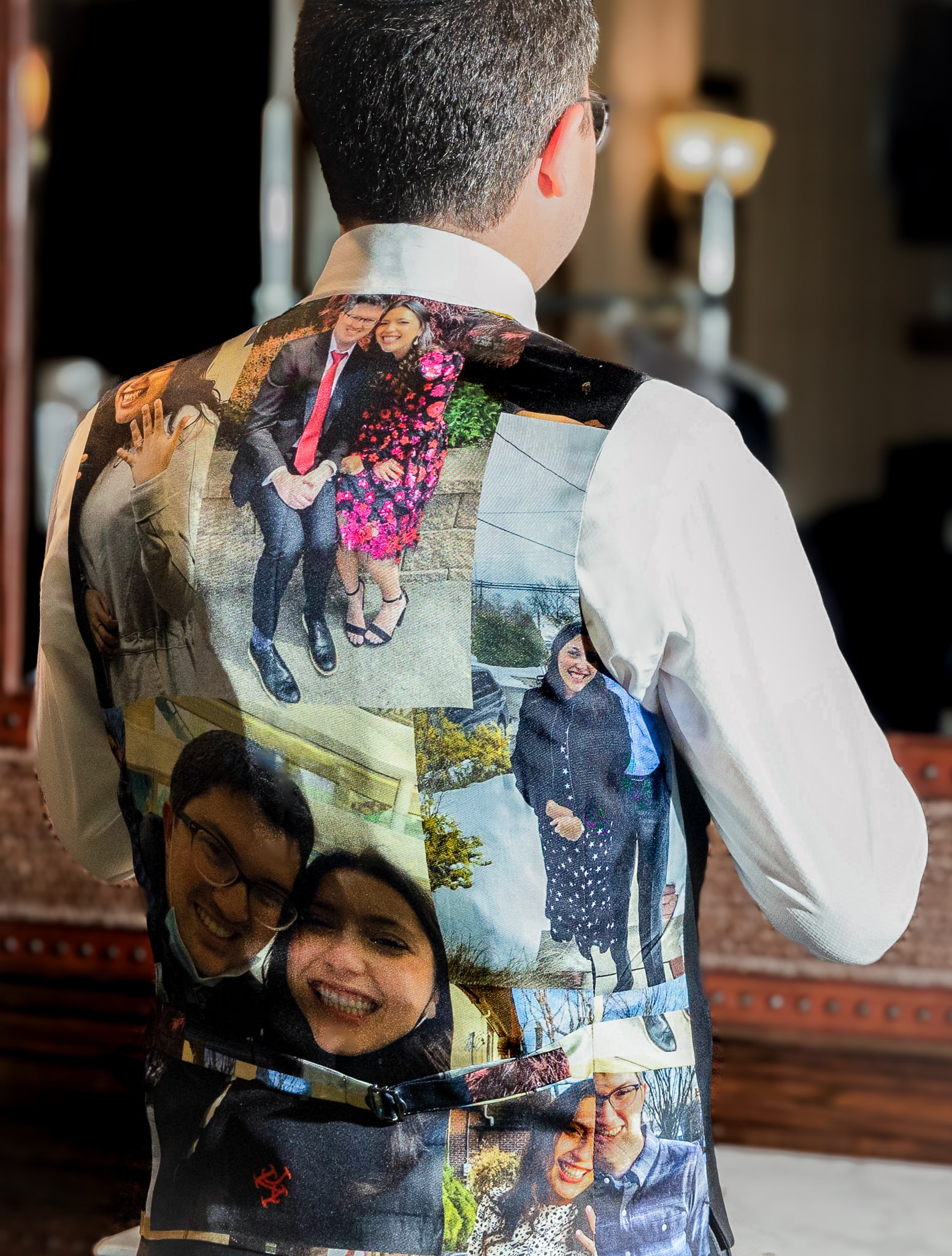 Owners son Benjamin Horowitz adjusting his bowtie in mirror. Wearing vest with photos of bride and groom screened onto back of vest.