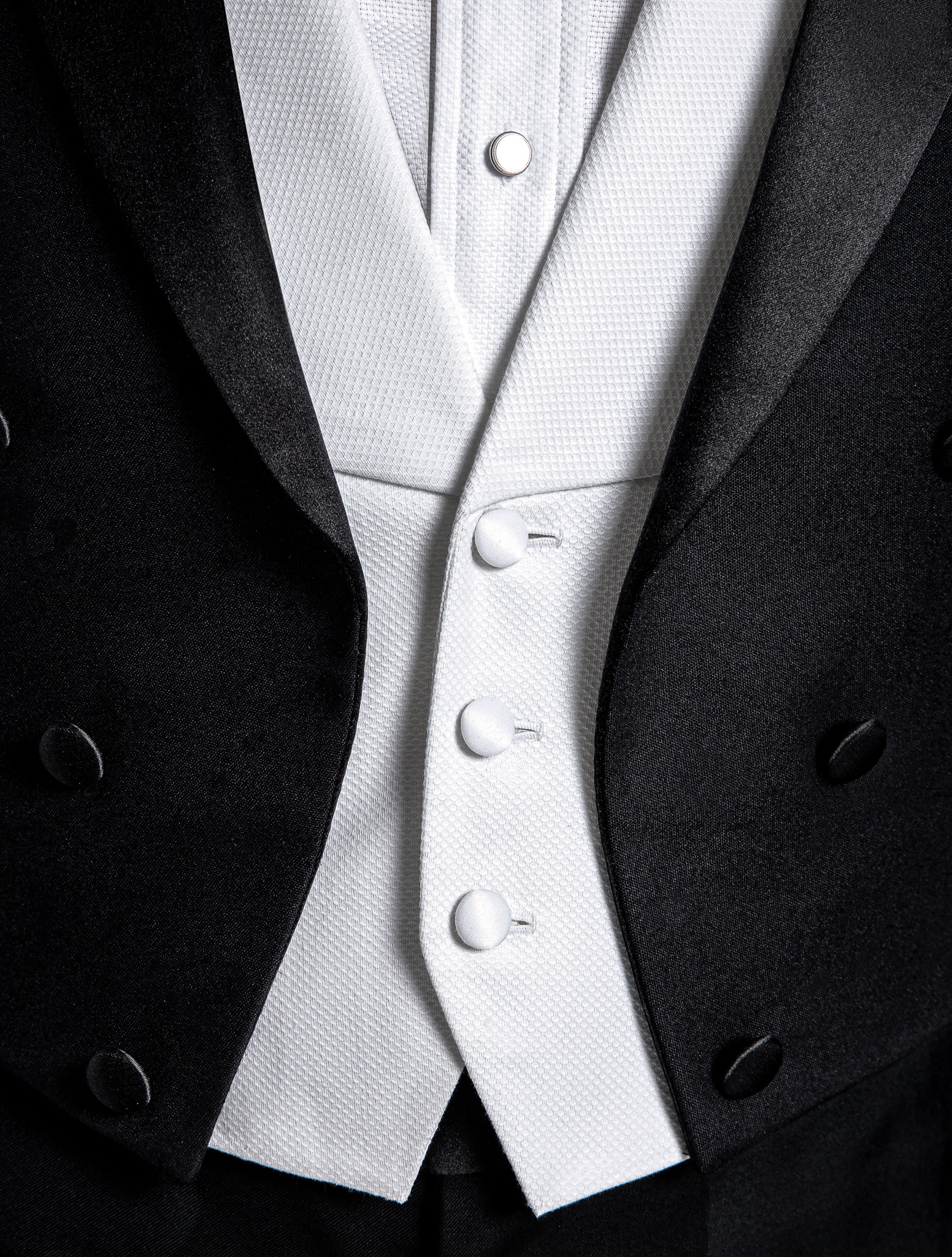 Close up of white pique vest worn under tuxedo wedding tails.