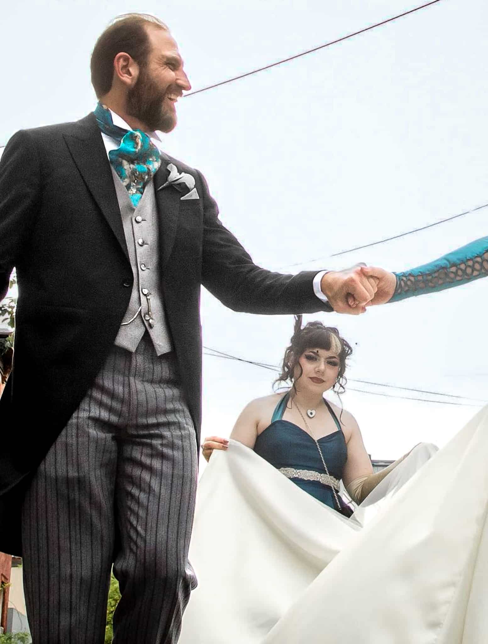 Groom shaking hands with groomsman wearing black custom morning coat with light grey waistcoat and grey stripe morning trousers.