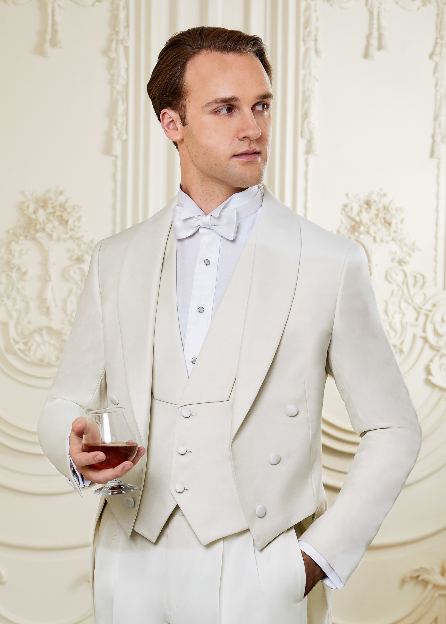 Model wearing white tails suit with matching vest. Jacket with shawl lapel, vest with cut in shawl lapel.