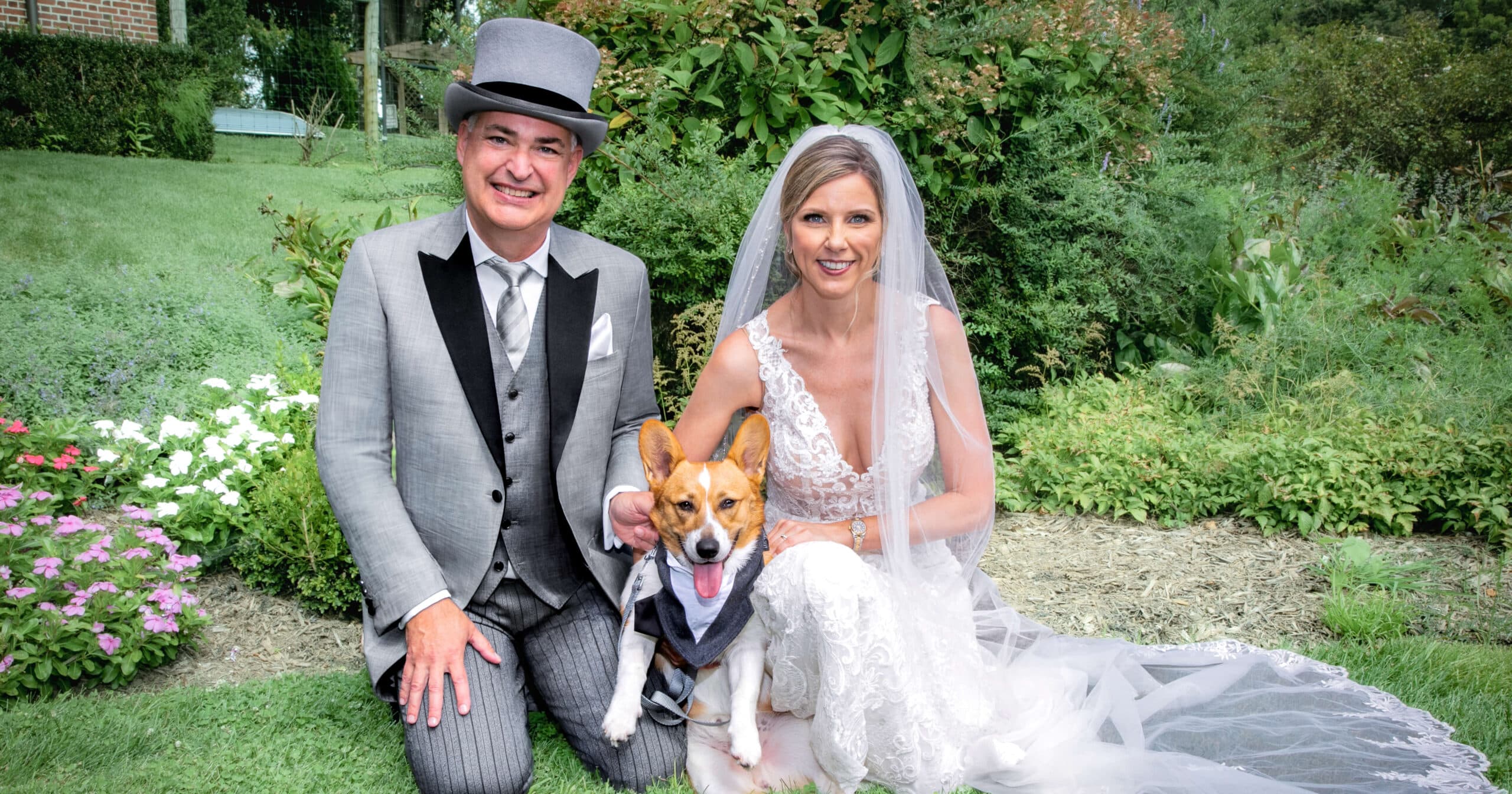 Bride and groom sitting outside with dog. Groom wearing light grey bespoke tailcoat with light grey top hat.