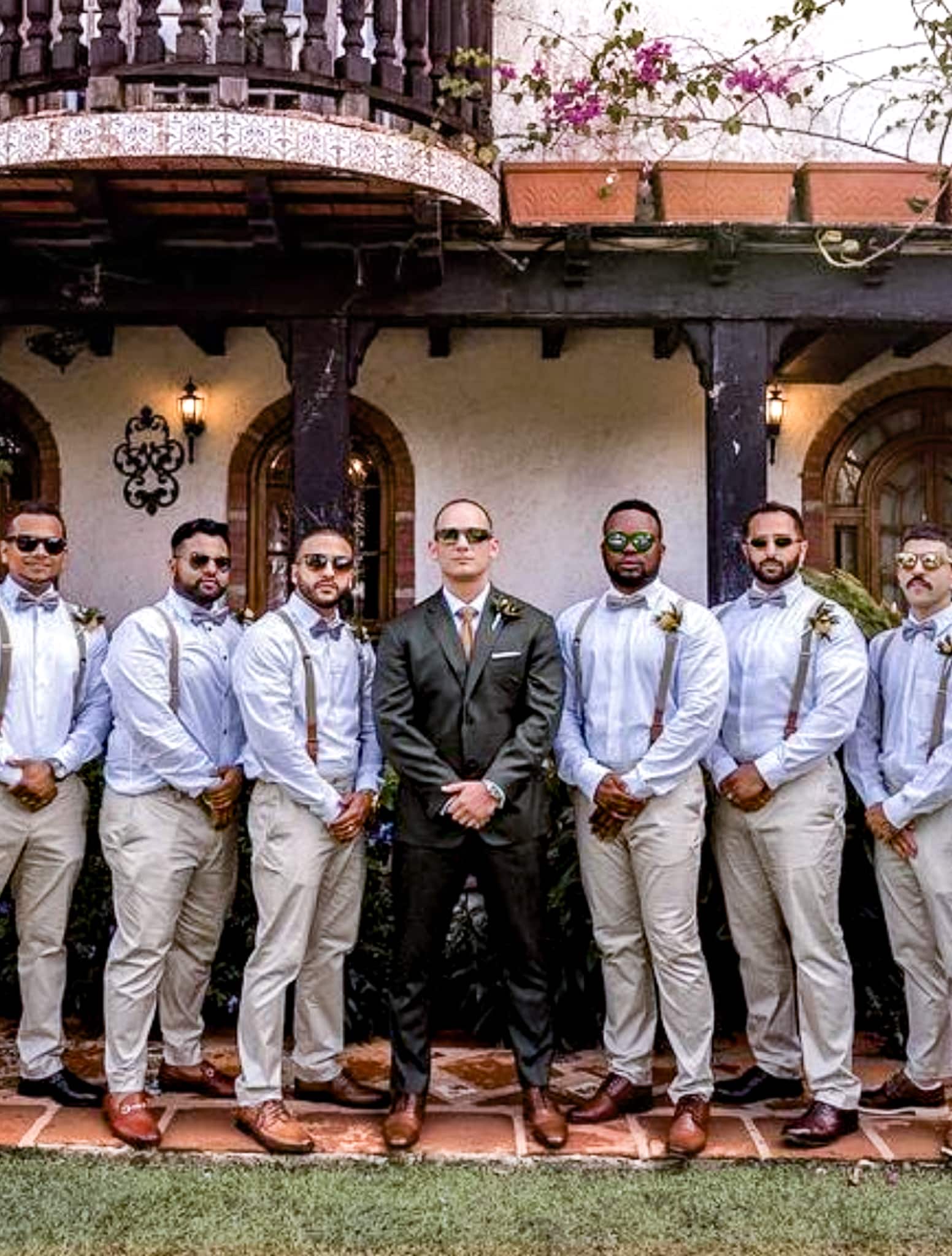 Six groomsmen standing with groom. Groom wearing green solid wedding suit with Zegna fabric.