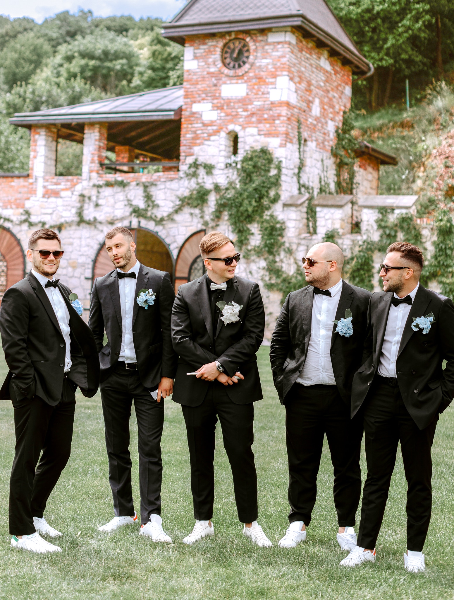 5 groomsmen all wearing black wedding tuxedos with black bowties.