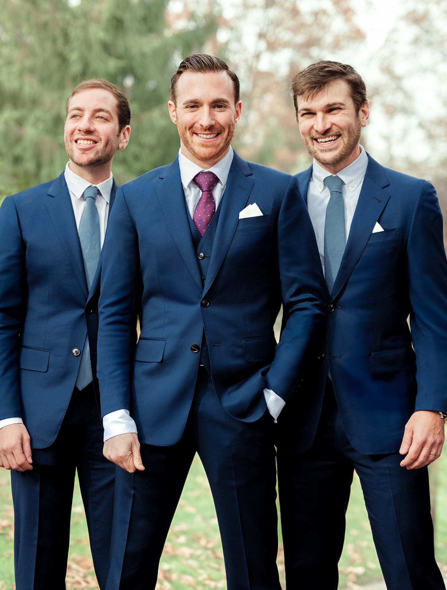 Three groomsmen all wearing navy blue wedding suits.
