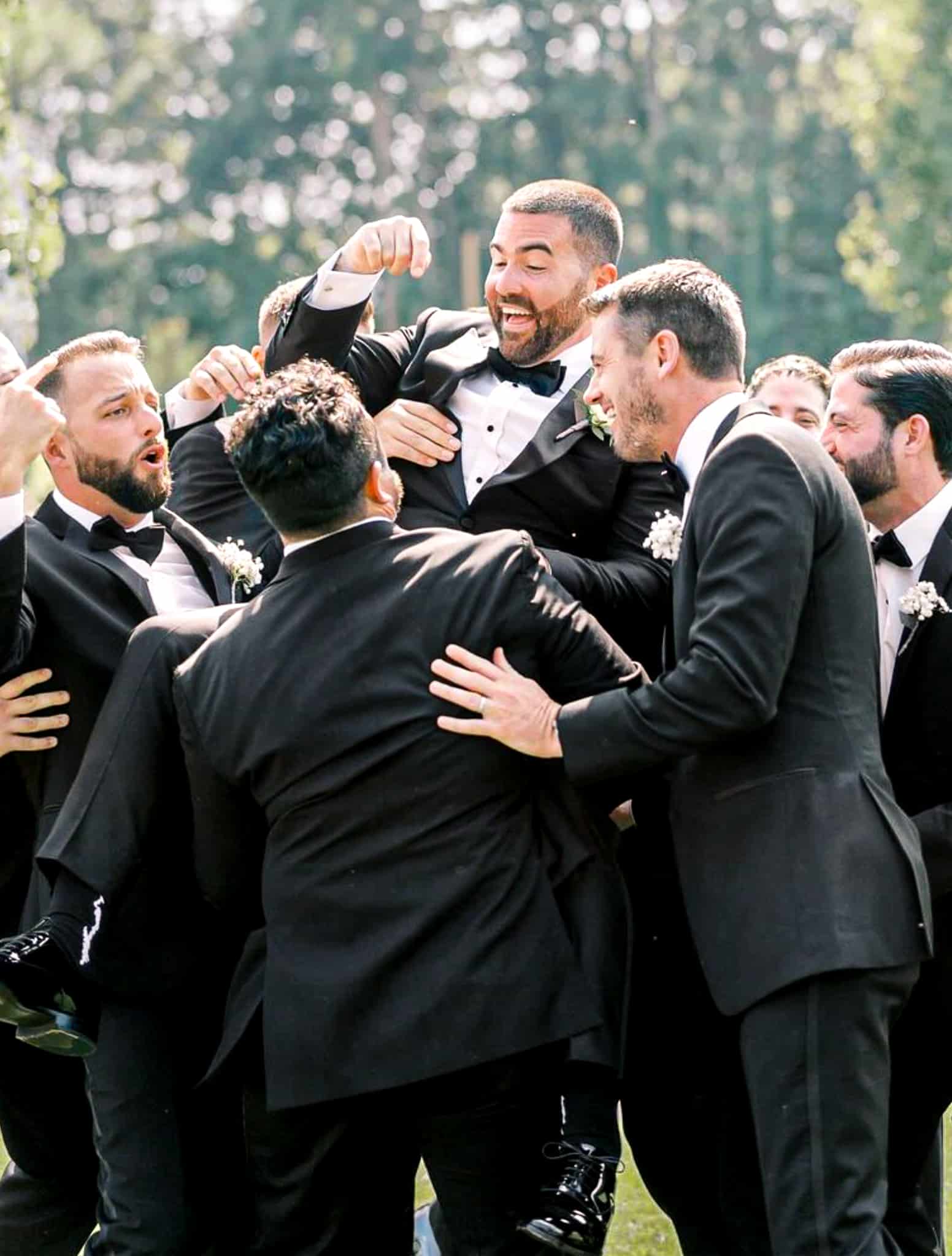 Five groomsmen dancing in a circle with groom. All wearing custom tailored wedding tuxedos.