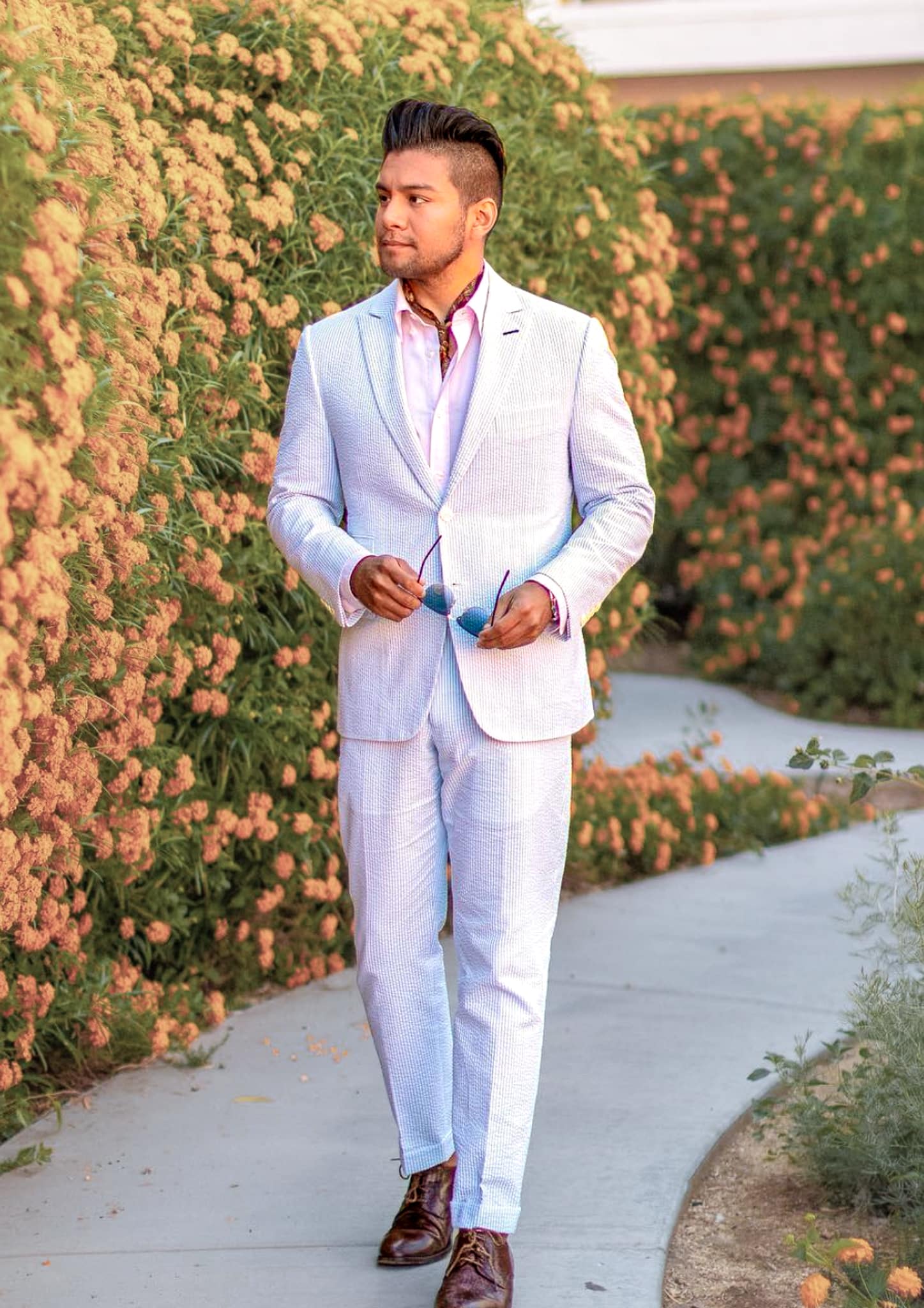 Groom wearing Scabal white bespoke wedding suit with white open collared shirt.