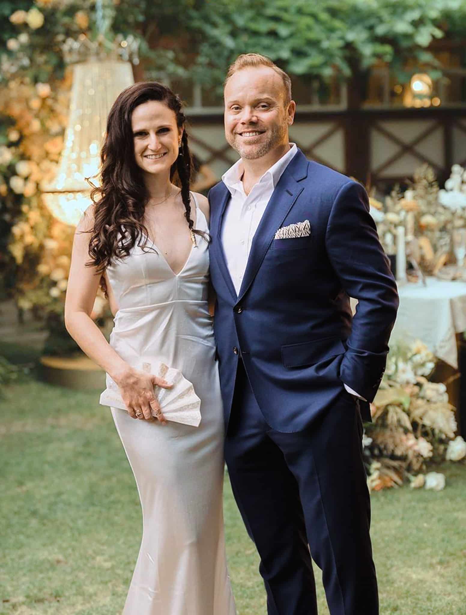 Bride and groom side by side. Groom wearing navy blue Loro Piana bespoke wedding suit with open collared white dress shirt.